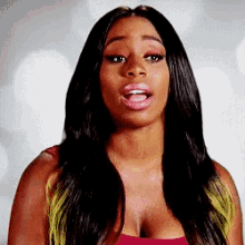 a woman with long black hair is wearing a red tank top with a plunging neckline