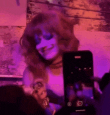 a woman in a wig is taking a picture of herself with a phone .
