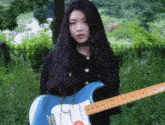 a woman with long hair is holding a blue electric guitar
