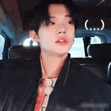 a young man is sitting in the back seat of a car and making a face .