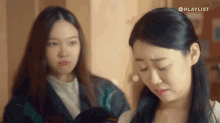 two women are standing next to each other with a playlist logo on the bottom right