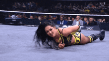 a female wrestler is laying on the floor in a wrestling ring with the letters w on the bottom