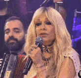 a woman singing into a microphone with an accordion in the background