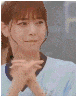 a close up of a woman making a face with her hands folded .