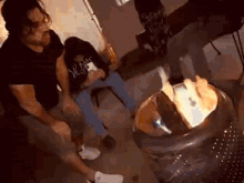 a couple of men are sitting around a fire pit .