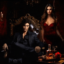 a woman in a red dress stands next to a man in a black suit