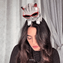 a woman has a stuffed cat on her head with sunglasses on