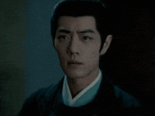 a close up of a man 's face in a dark room wearing a black jacket and a white shirt .