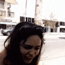 a woman wearing sunglasses stands on a sidewalk in front of a building that says ' abercrombie & fitch '