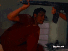 a man in a red shirt is holding a sword with the words keluarga man on the bottom