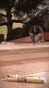 a woman squatting down next to a broken bottle with the letters viggle.ai on the bottom right