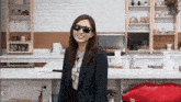 a woman wearing sunglasses stands in a kitchen with a welcome sign