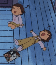 two little girls are laying on a wooden floor with a book on the floor