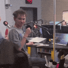 a man sitting at a desk with a microphone in front of him and a sign that says ' a ' on it