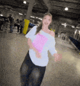 a woman wearing a white t-shirt with a pink sticker on it