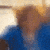 a blurry picture of a person 's face with a blue jacket on