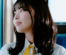 a woman wearing a white shirt and a yellow tie looks to the side