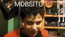 a young man is making a funny face in front of a shelf with toys on it .