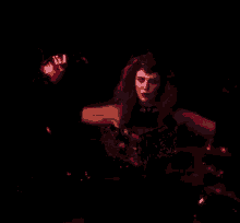 a woman in a black dress is holding a red object in her hand in the dark .