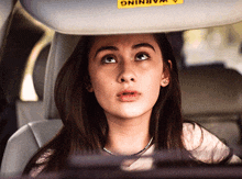 a woman is sitting in a car with a warning sign on the sun visor
