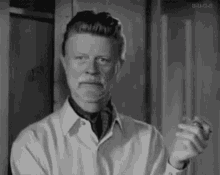 a man with a beard is smoking a cigarette and making a funny face in a black and white photo .