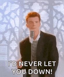 a man in a suit is singing into a microphone and saying " i 'd never let you down "