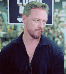 a man with a beard wearing a blue shirt is standing in front of a sign that says lunch