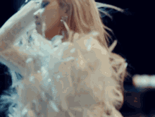 a woman in a white dress with feathers covering her face