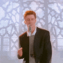 a man is singing into a microphone with his eyes closed