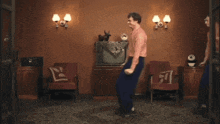 a man in a pink shirt is dancing in a room
