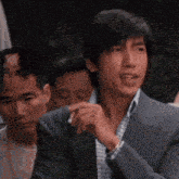 a man in a suit is smoking a cigarette in a crowd