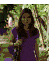 a woman in a purple shirt is walking down a sidewalk holding a purse .