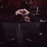 a person making a heart shape with their hands in front of a monitor that says alien