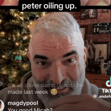 a man with a beard is sitting in front of a christmas tree and says peter oiling up