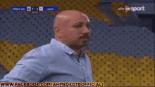 a man in a blue shirt stands in front of a stadium with the words www.facebook.com/ahmedkotbofficial1