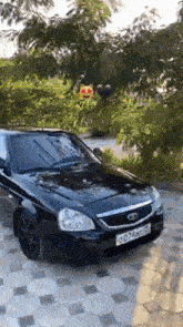a black car is parked on a tiled driveway in a park .