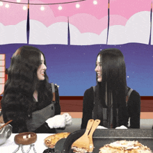 two women are sitting at a table with a tray of food