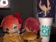 three stuffed dolls are eating a hamburger and french fries next to a mcdonalds cup