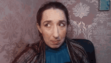 a woman wearing a scarf and a blue shirt is making a face