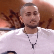 a man with a beard wearing a white shirt and a necklace .