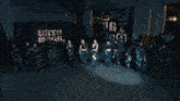 a group of women are dancing in a dark room and one of them is wearing a black top