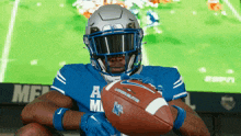 a football player holds a football in front of a screen that says espn on it