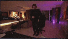 a blurry picture of a man dancing in a room with purple lights