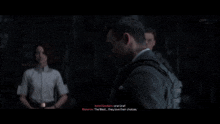 a man in a suit is talking to a woman and another man