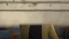 a woman in a yellow jacket is standing in front of a wall .