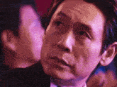 a close up of a man 's face with a purple light behind him