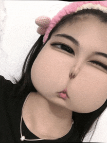 a girl wearing a pink headband making a face