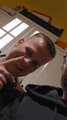 a man with glasses is pointing at another man 's nose