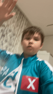 a boy wearing a blue jacket with a red x on the chest