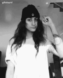 a black and white photo of a woman wearing a beanie and a white t-shirt